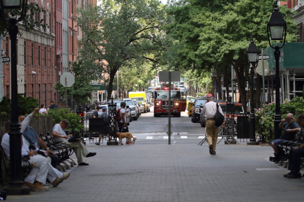 FDNY NYC fire truck sitting on Washington Place with lights on outside Washington Square Park full of people