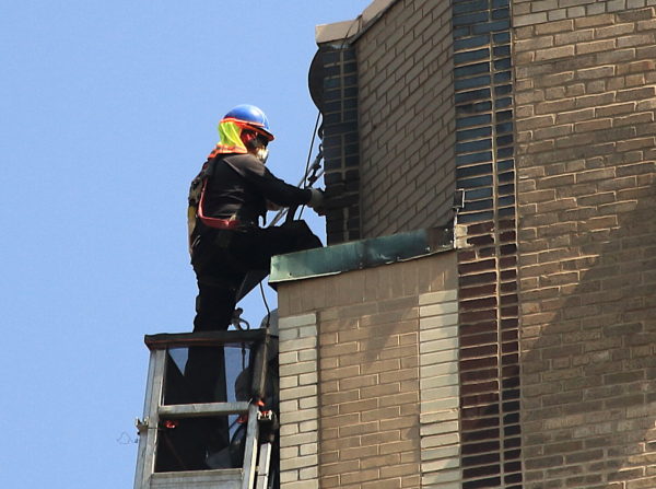 Worker renovating One Fifth Avenue NYC near a Hawk perch
