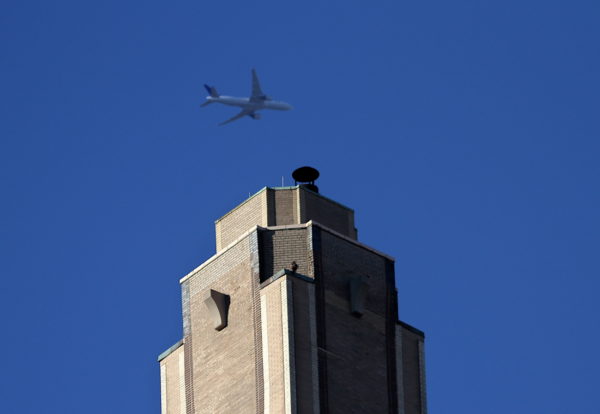 Plane flies past Sadie seated on apartment building